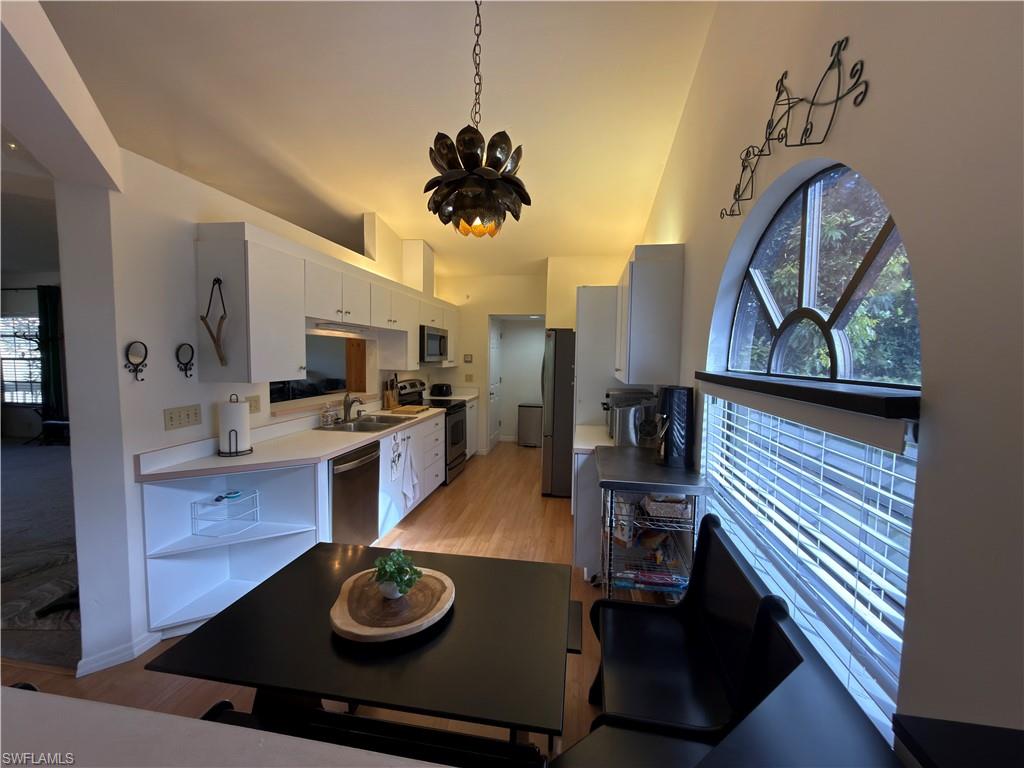 Kitchen featuring light countertops, stainless steel appliances, light wood-style floors, white cabinetry, and healthy amount of natural light