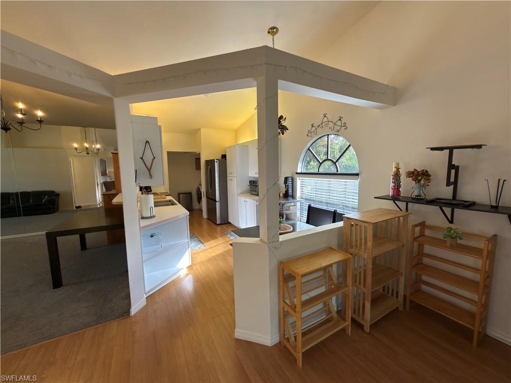 Kitchen featuring light wood-style floors, freestanding refrigerator, white cabinets, and light countertops