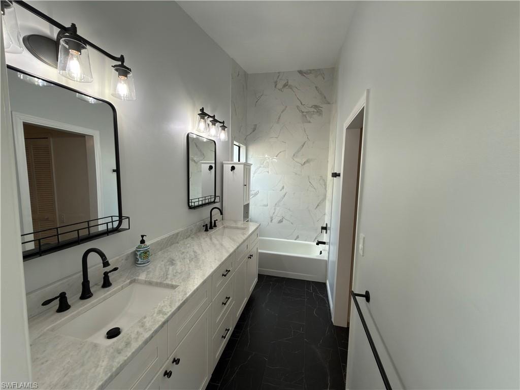 Bathroom featuring double vanity and dark marble finish floors