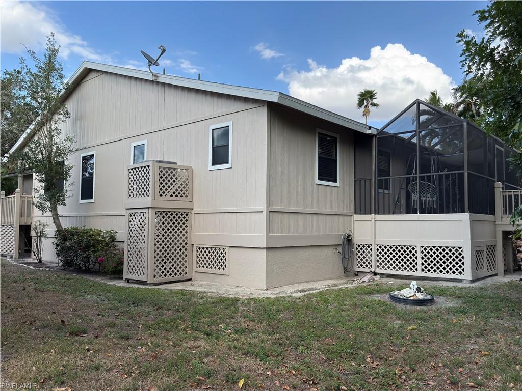 View of side of home featuring a sunroom, a yard, a lanai, and a wooden deck