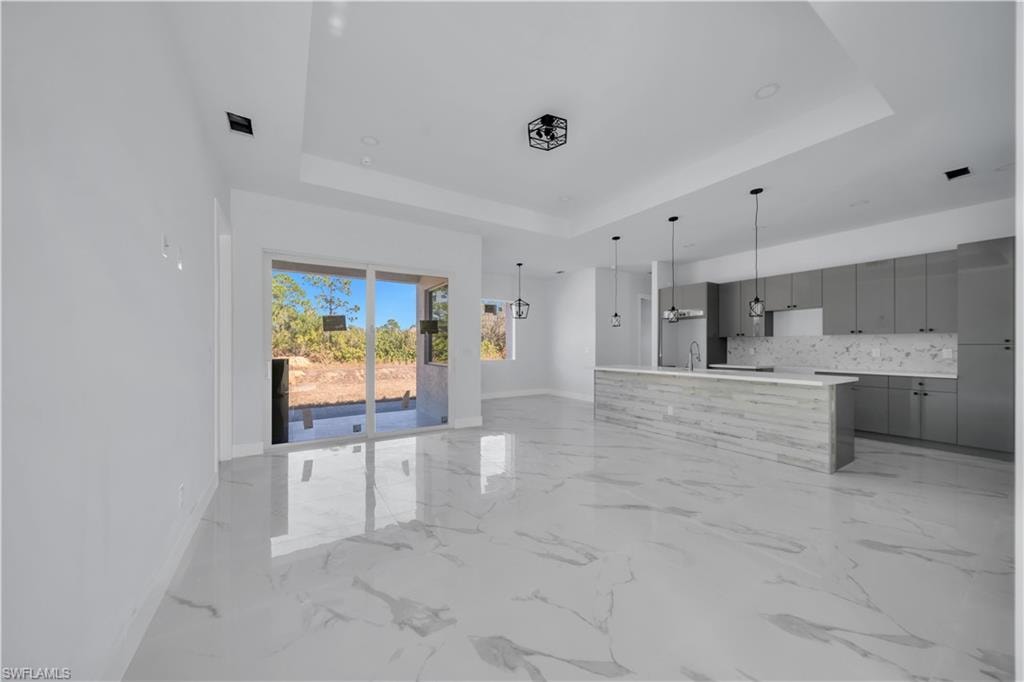 Unfurnished living room featuring baseboards and a chandelier