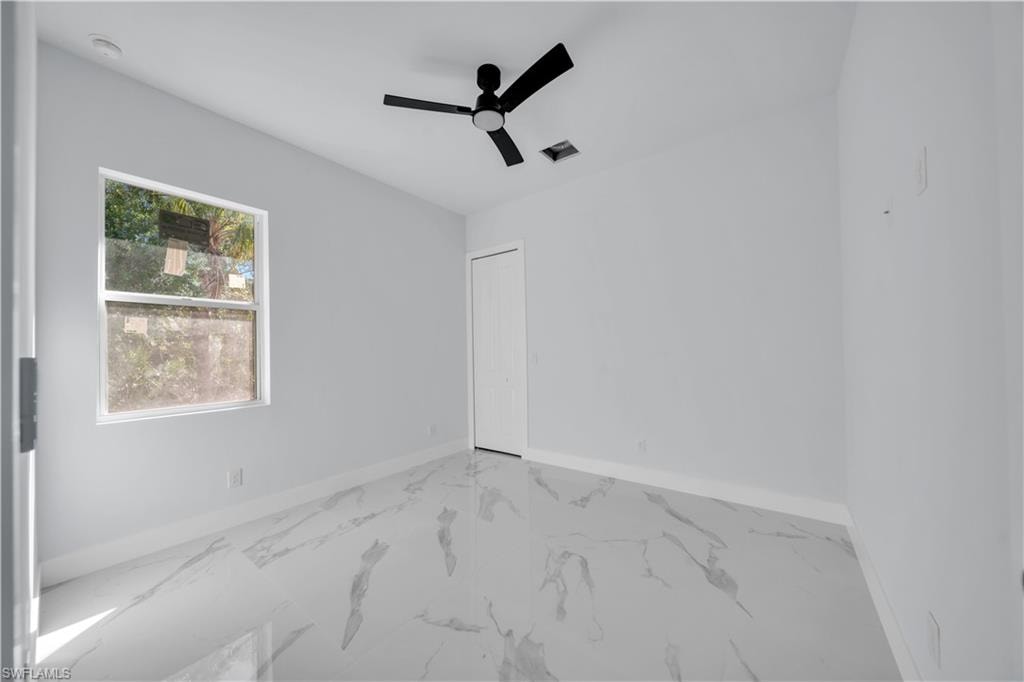 Spare room featuring light marble finish flooring and ceiling fan