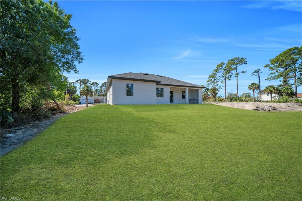 Back of property featuring a yard and stucco siding