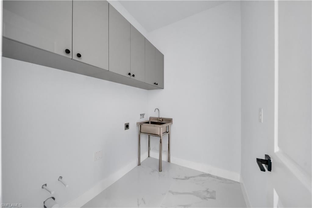 Laundry room with hookup for an electric dryer, light marble finish flooring, cabinet space, and hookup for a washing machine