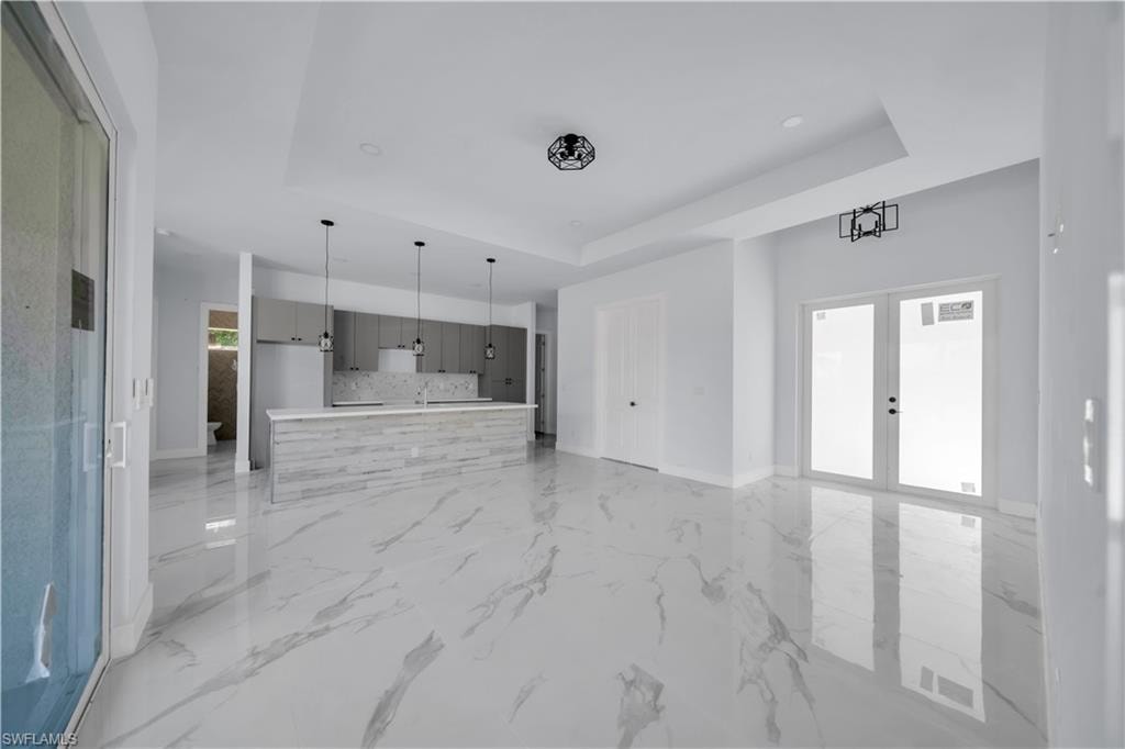 Unfurnished living room with a raised ceiling and french doors