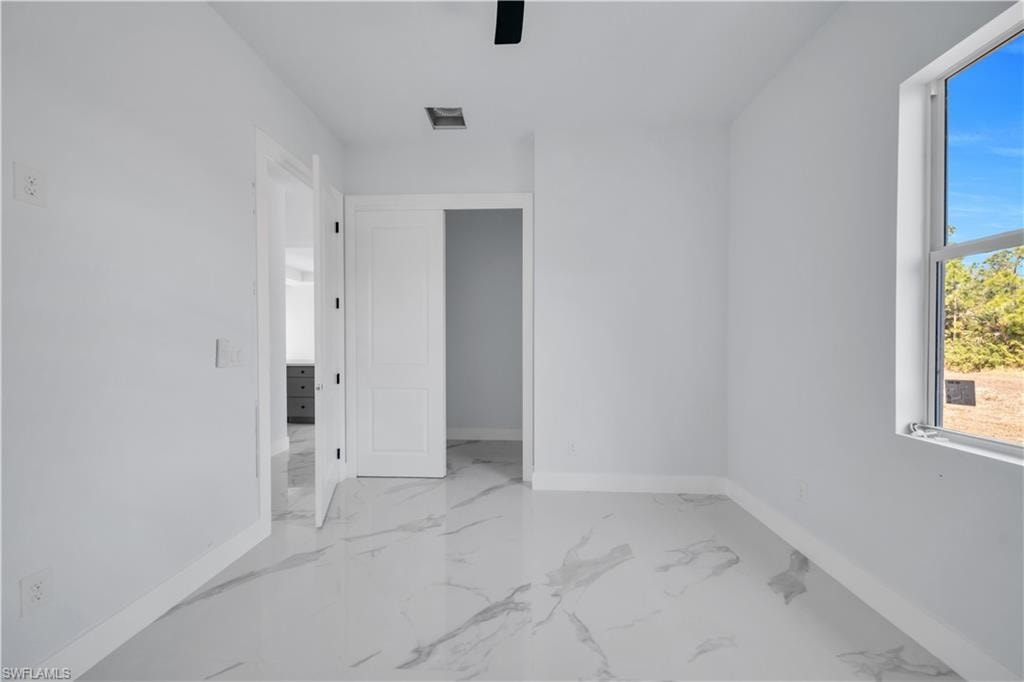 Spare room featuring baseboards and light marble finish floors