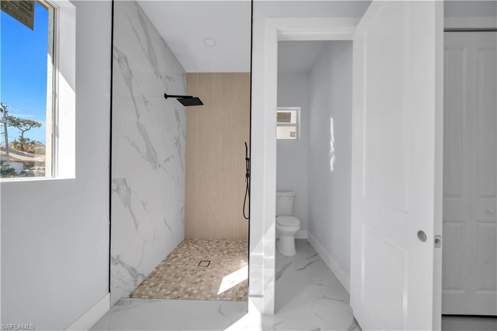 Bathroom featuring a marble finish shower and light marble finish floors