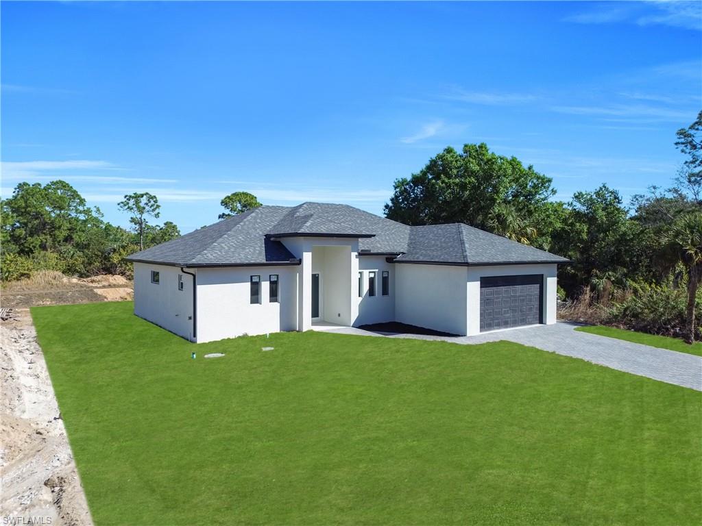 View of front facade with a front yard, an attached garage, stucco siding, and decorative driveway