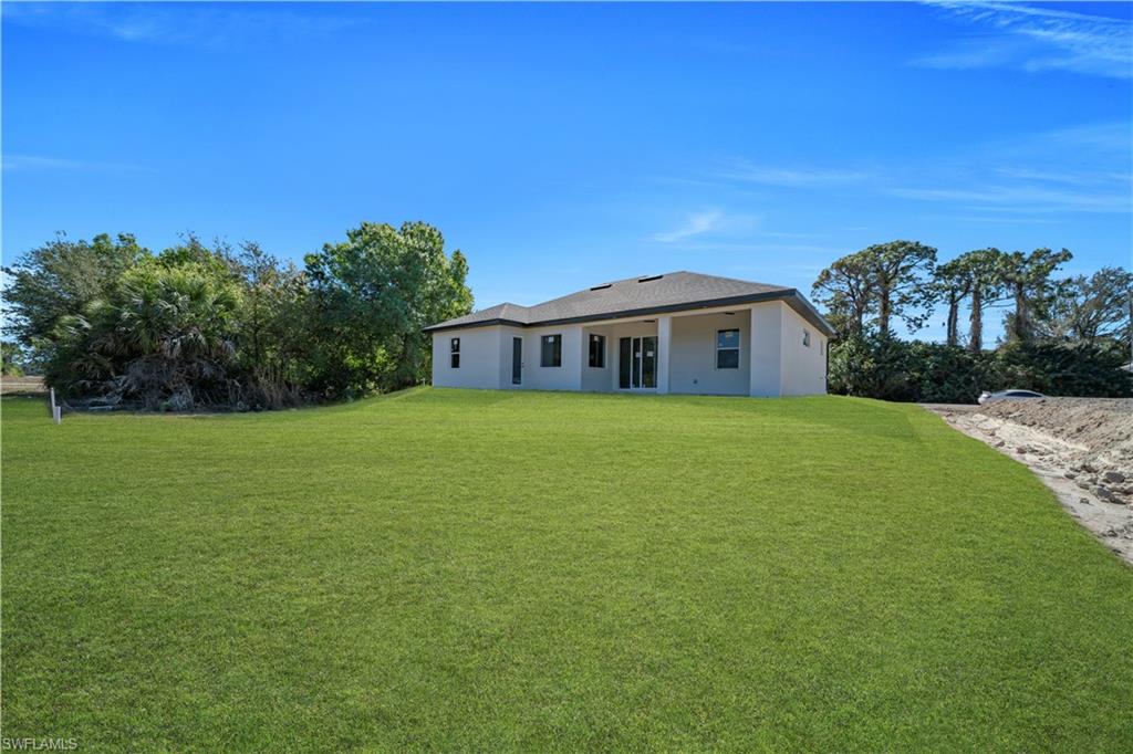 Rear view of house featuring a yard, stucco siding, and a patio area