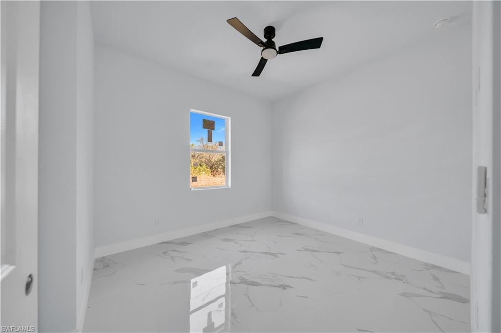 Unfurnished room featuring a ceiling fan and light marble finish floors