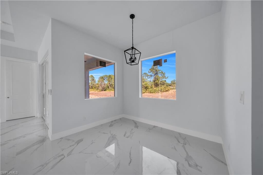 Unfurnished dining area featuring light marble finish floors and suspended lighting