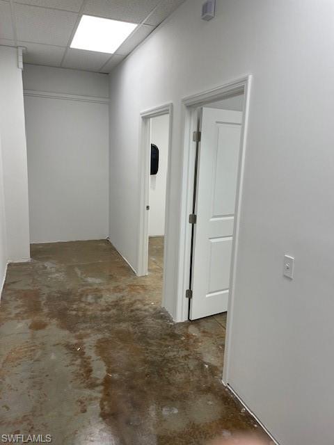 Hall featuring concrete flooring and a paneled ceiling