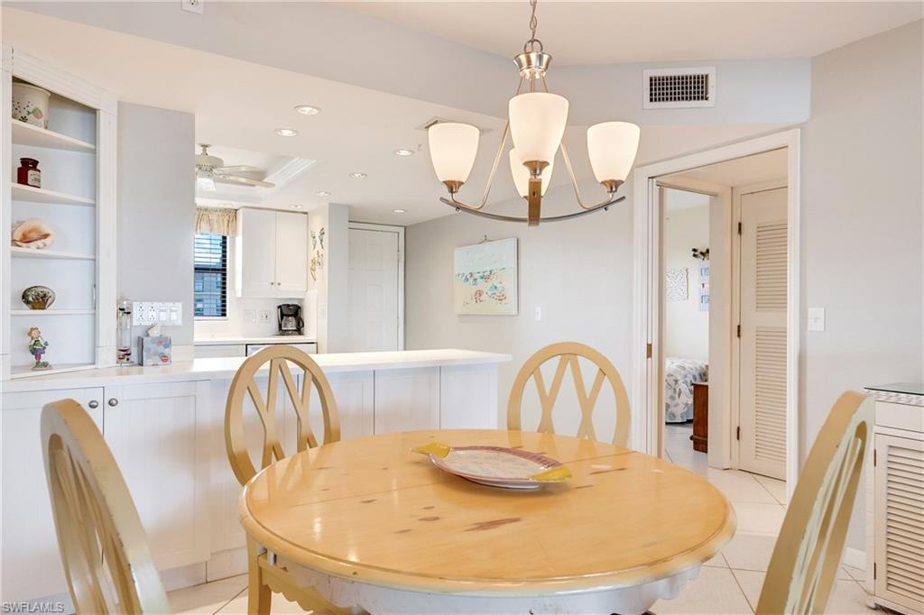 Dining room with light tile patterned flooring, a tray ceiling, suspended lighting, and a ceiling fan