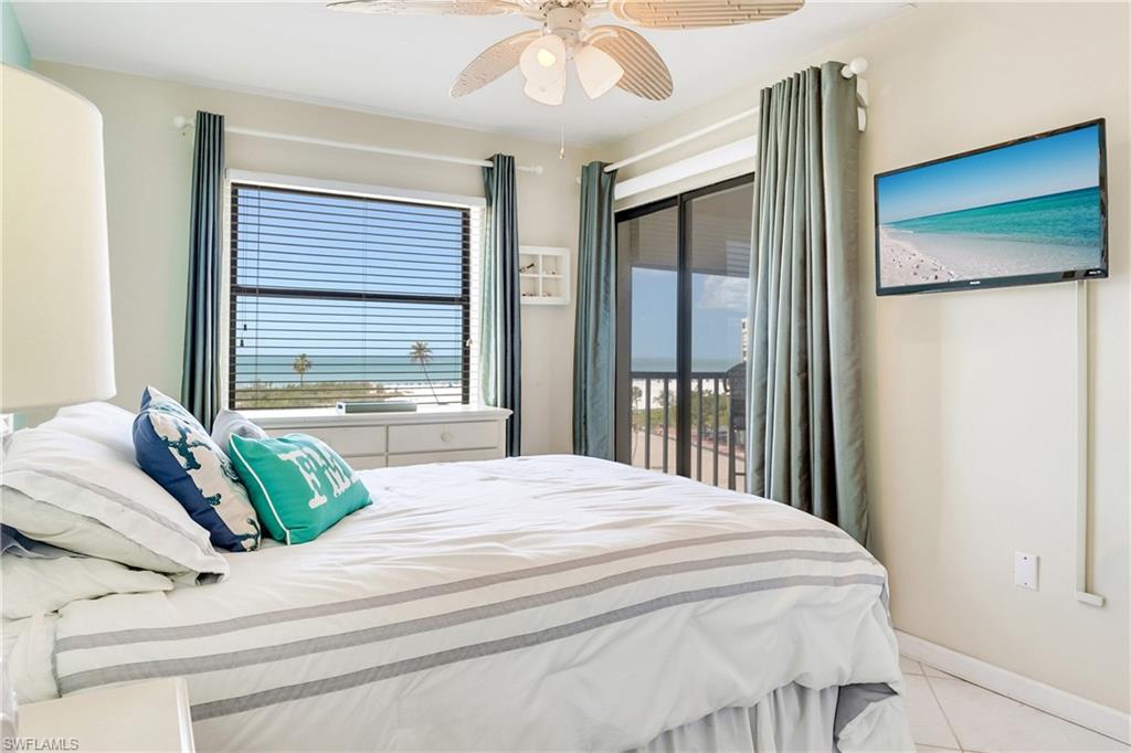Bedroom with multiple windows, access to outside, a ceiling fan, and light tile patterned flooring