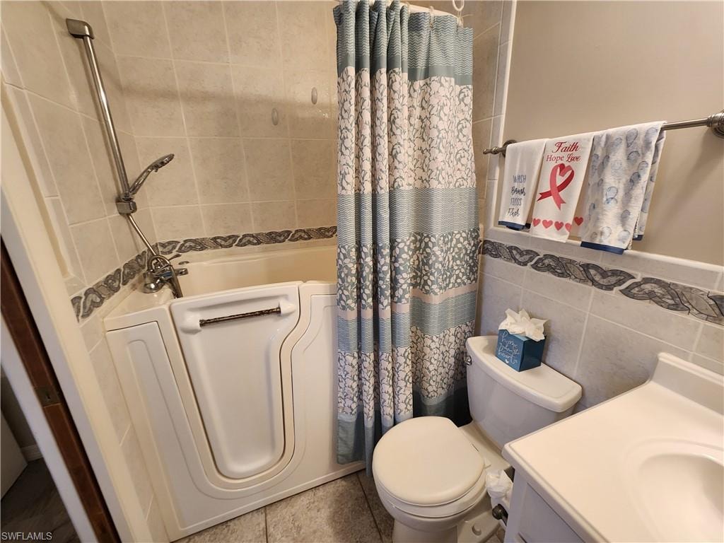 Full bath with tile walls, vanity, and shower / tub combo