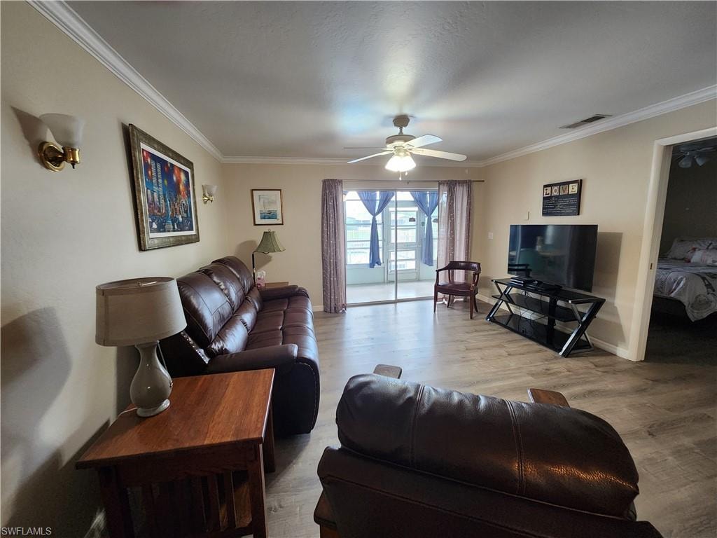 Living area featuring light wood-style flooring, a ceiling fan, and ornamental molding