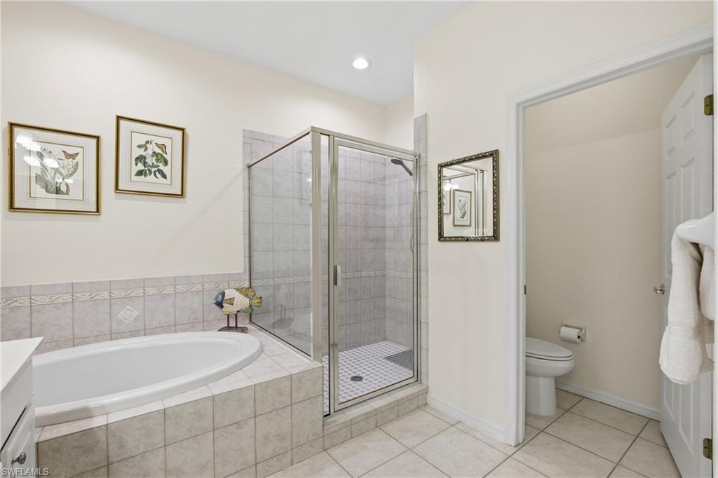 Bathroom featuring a stall shower, a bath, light tile patterned floors, and vanity