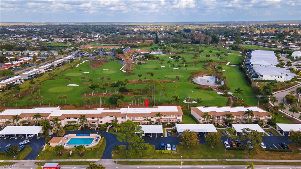 View of property location featuring a golf club, a large body of water, and nearby suburban area