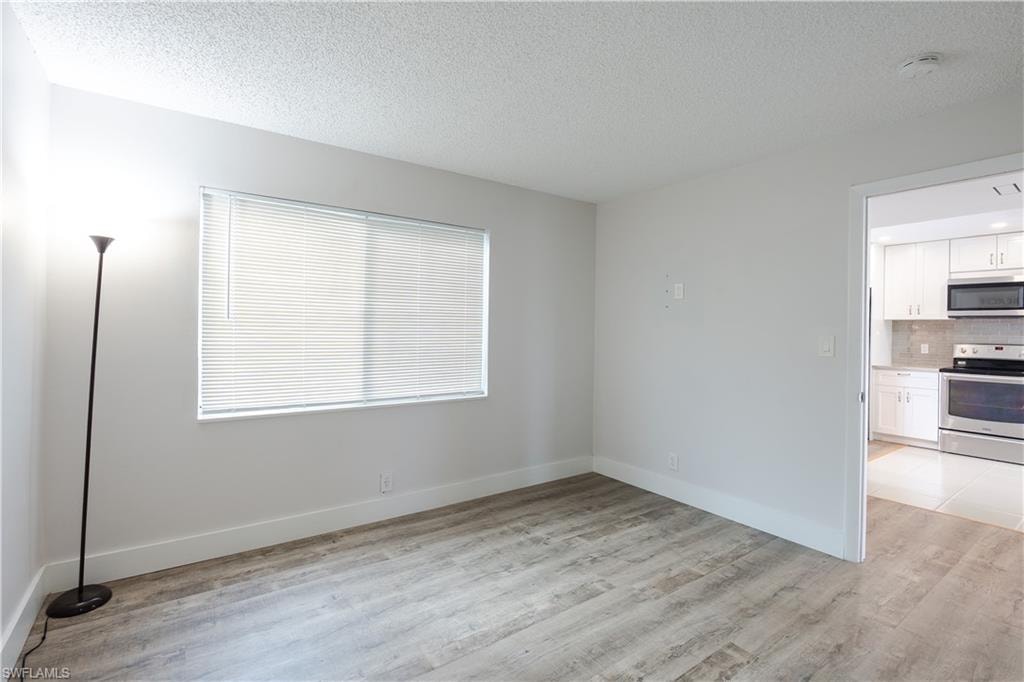 Spare room with a textured ceiling and light wood-style floors