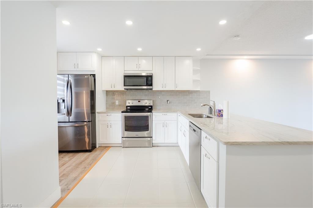 Kitchen with open shelves, stainless steel appliances, recessed lighting, light tile patterned floors, and a peninsula