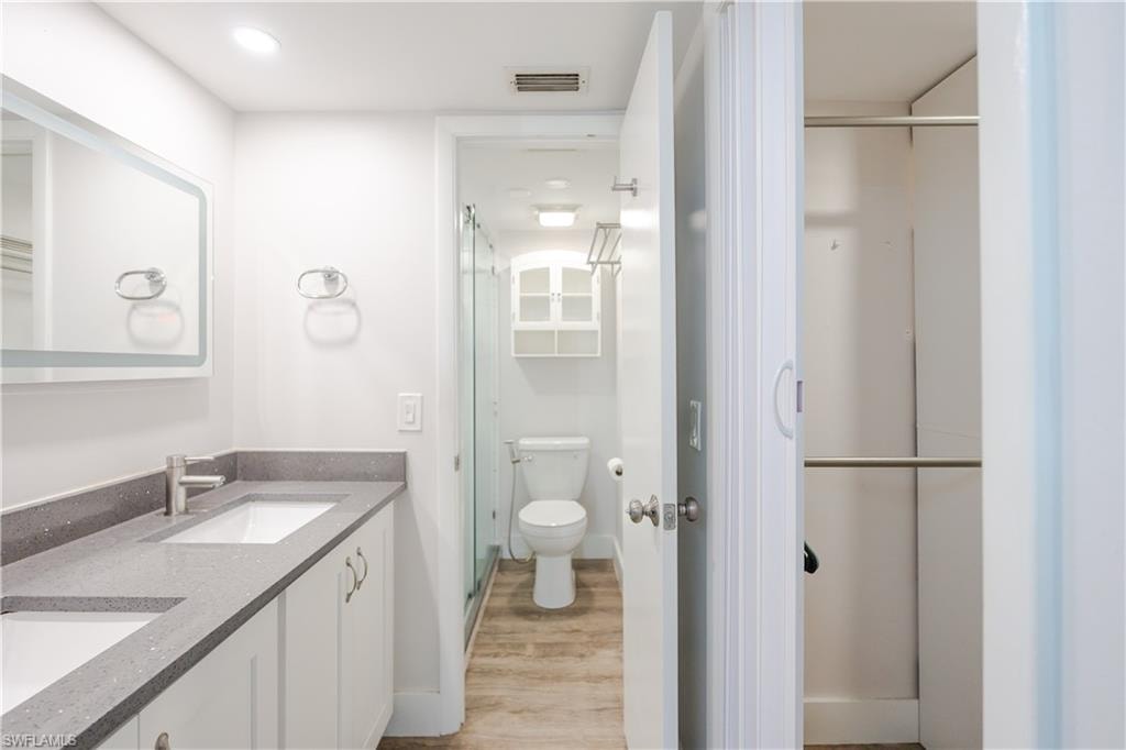 Bathroom featuring double vanity, light wood-style flooring, and a stall shower