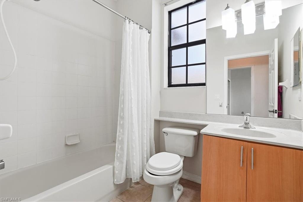 Full bathroom featuring vanity, shower / bath combination with curtain, and light tile patterned flooring