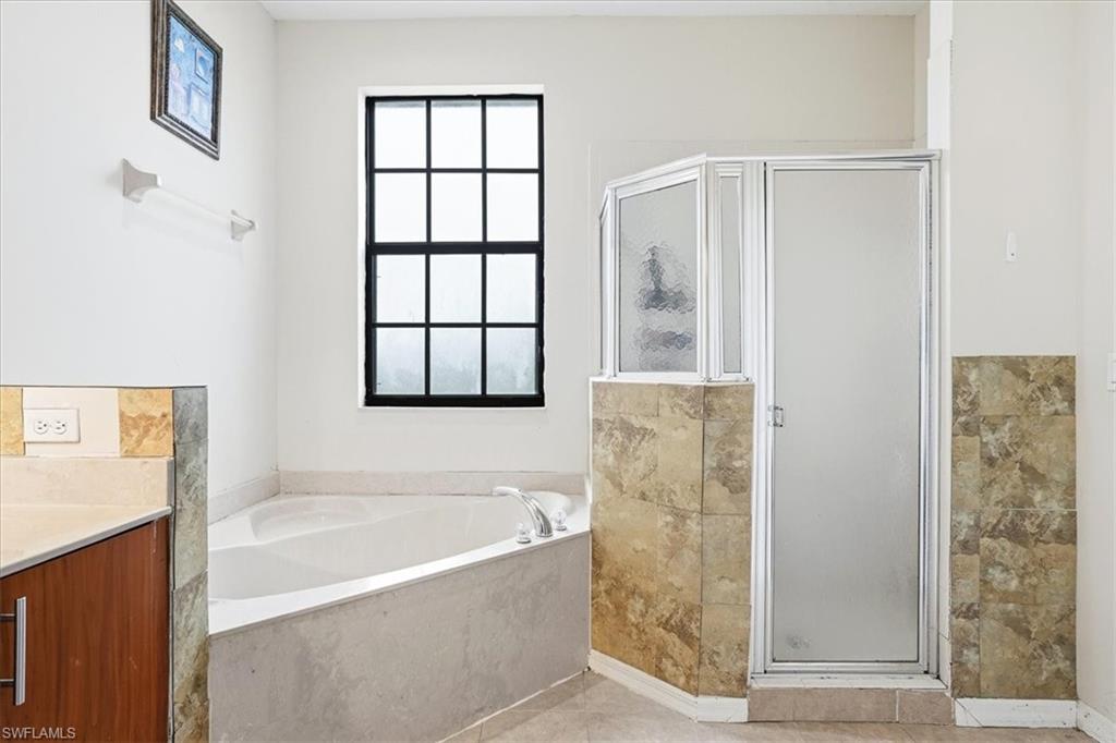 Bathroom with a stall shower, a bath, vanity, and light tile patterned floors