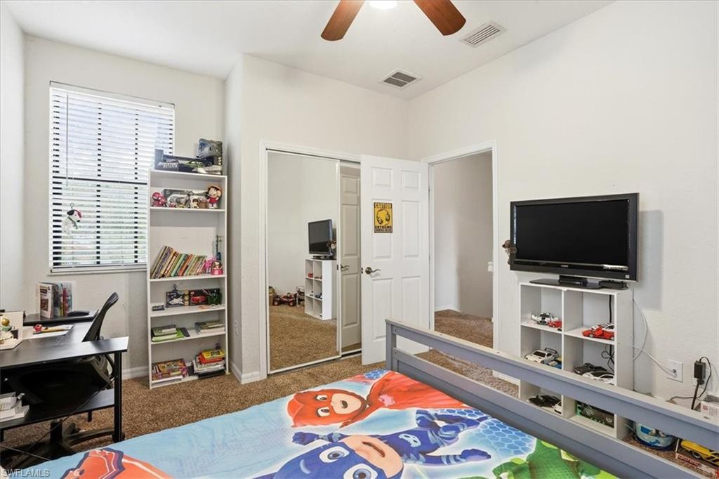 Bedroom featuring dark colored carpet, ceiling fan, a closet, and a desk