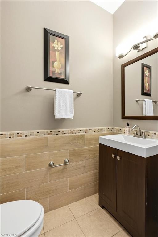 Bathroom with vanity, tile walls, light tile patterned flooring, and wainscoting