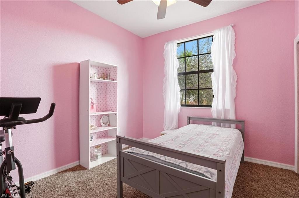 Carpeted bedroom featuring a textured wall and ceiling fan