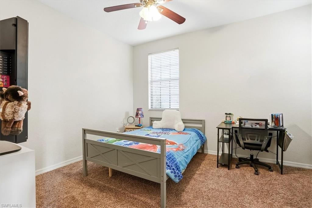 Carpeted bedroom with a ceiling fan and a desk
