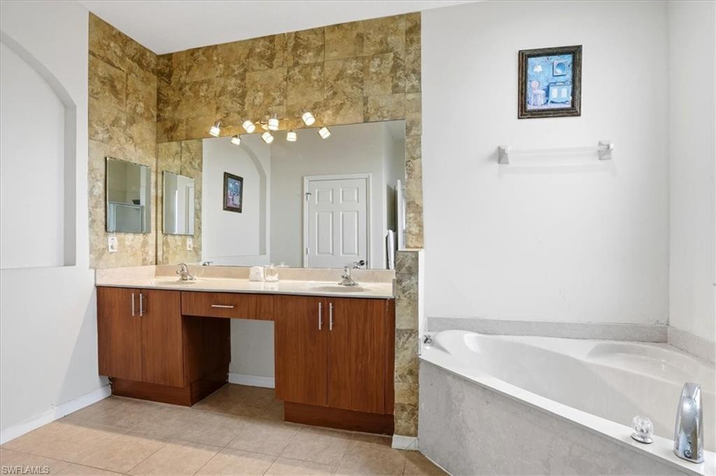 Bathroom with double vanity, a garden tub, and light tile patterned flooring