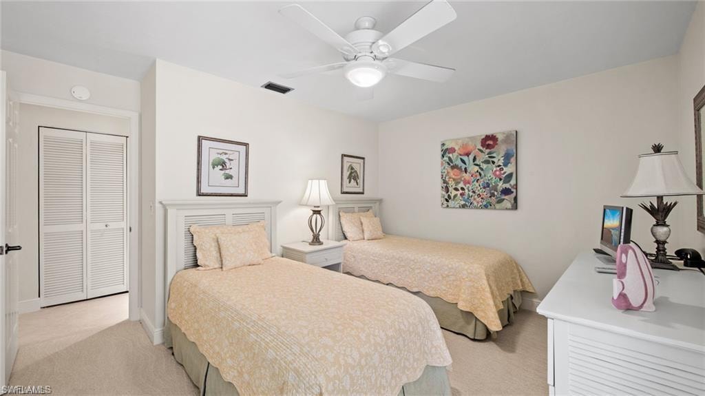 Bedroom with light carpet, ceiling fan, and a closet