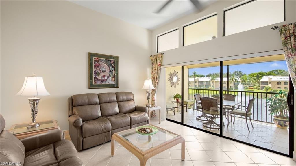 Tiled living room featuring plenty of natural light, a high ceiling, and a ceiling fan