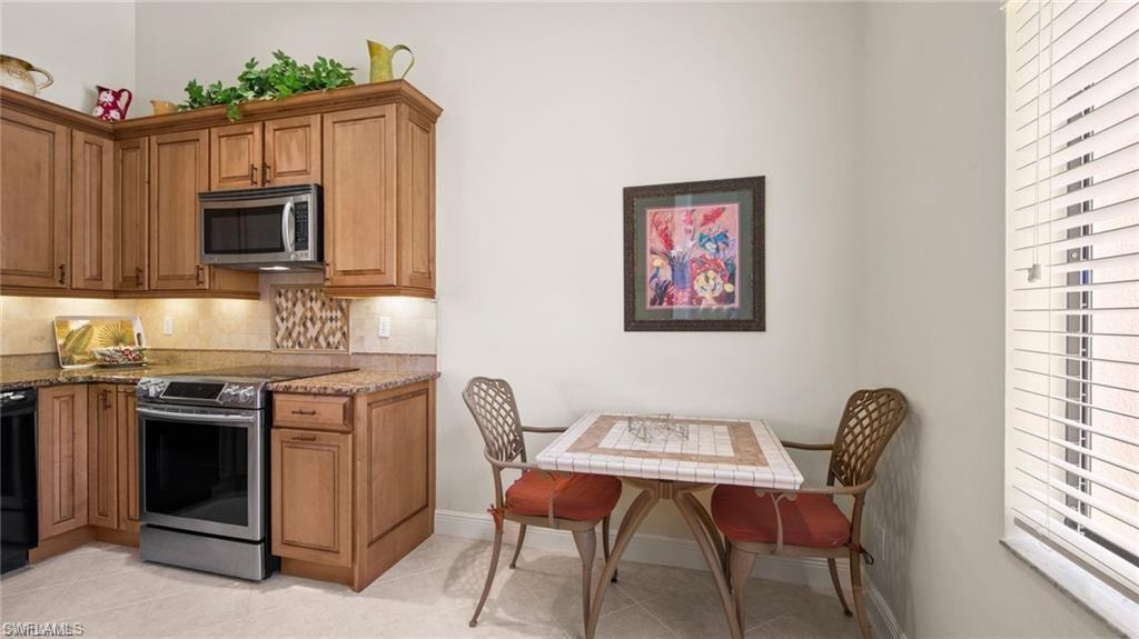 Kitchen with stainless steel appliances, light stone countertops, wood finish cabinetry, and light tile patterned floors
