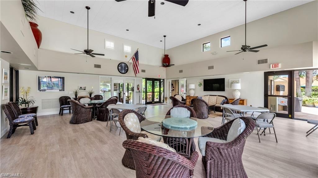 Dining room featuring a high ceiling, light wood-style floors, a ceiling fan, and french doors