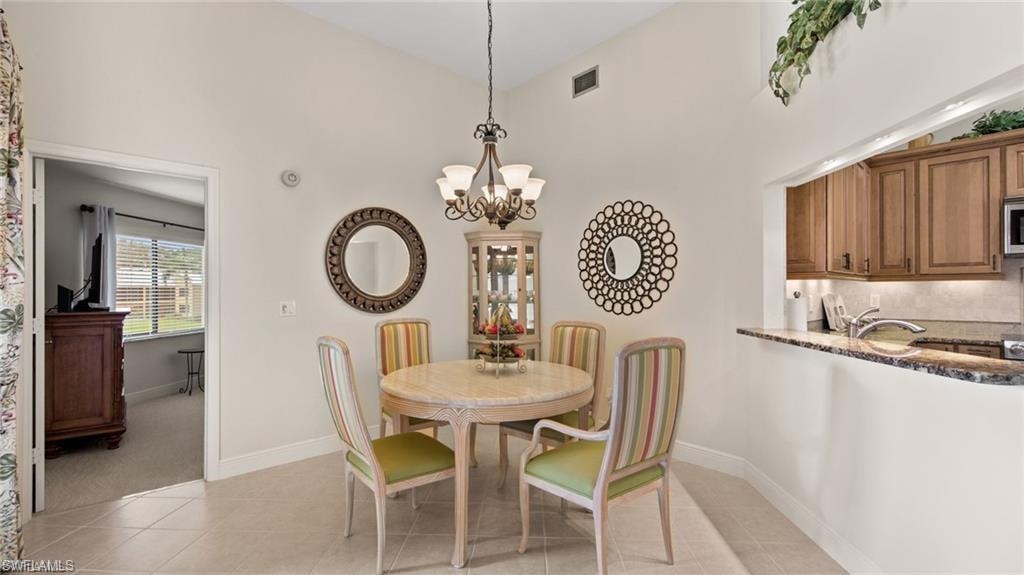 Dining room with suspended lighting, light tile patterned floors, and vaulted ceiling