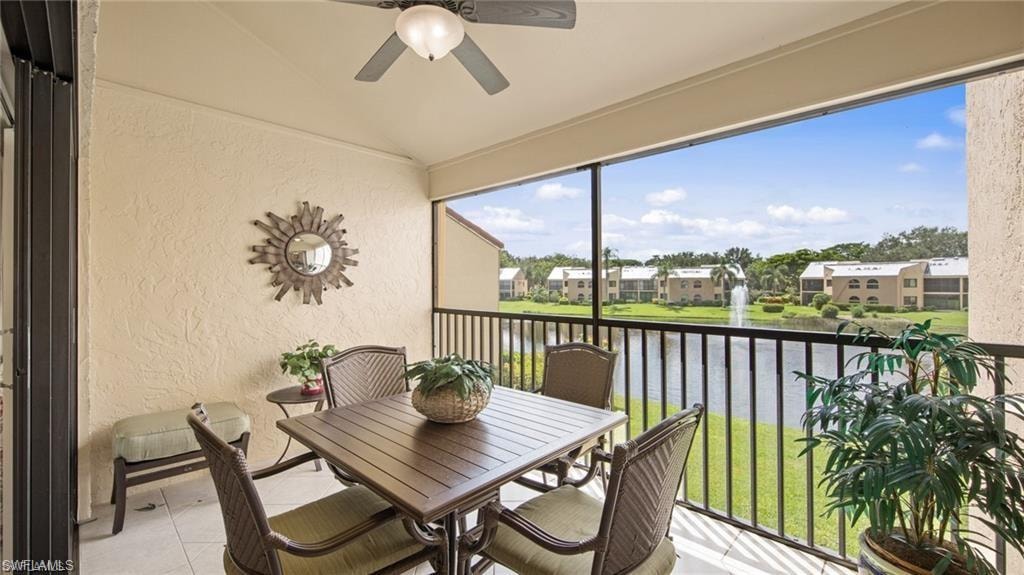 Sunroom with a ceiling fan, vaulted ceiling, a balcony, outdoor dining area, and a water view