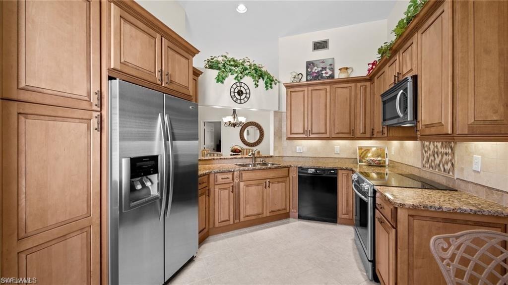 Kitchen with stainless steel appliances, light stone countertops, wood finish cabinets, and hanging lights