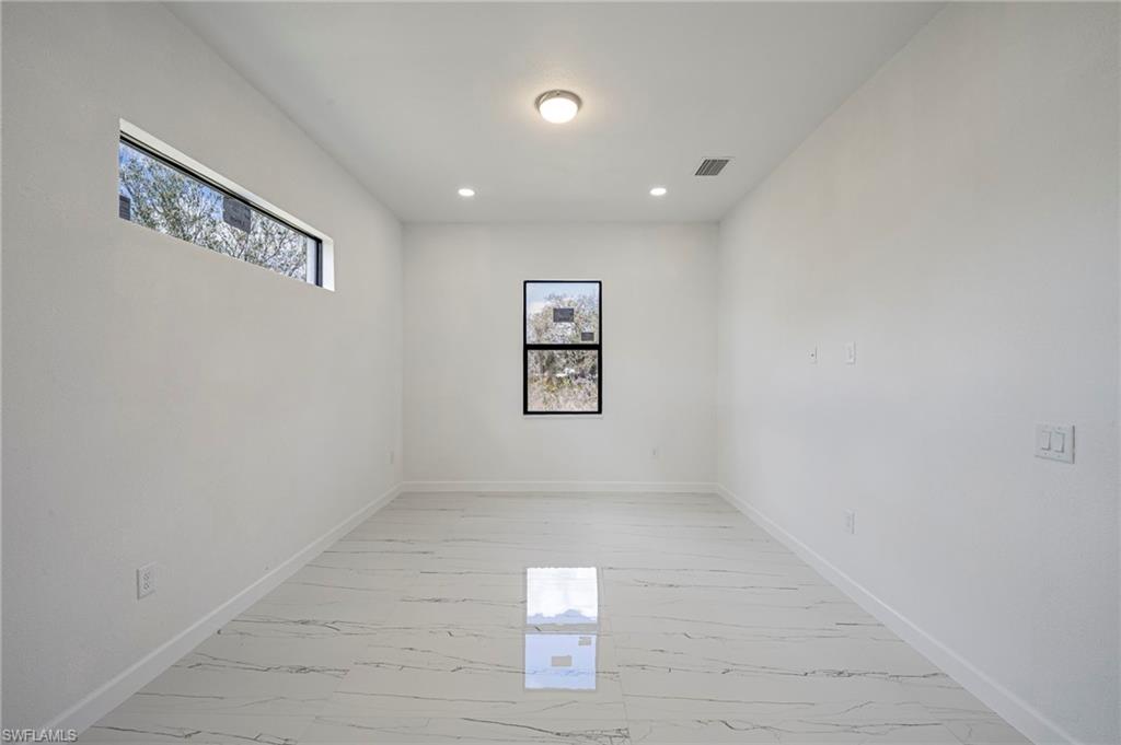 Unfurnished room with healthy amount of natural light, light marble finish flooring, and recessed lighting