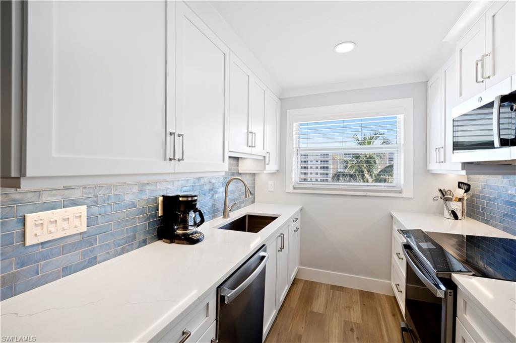 Kitchen featuring stainless steel appliances, light wood-style flooring, decorative backsplash, white cabinets, and recessed lighting