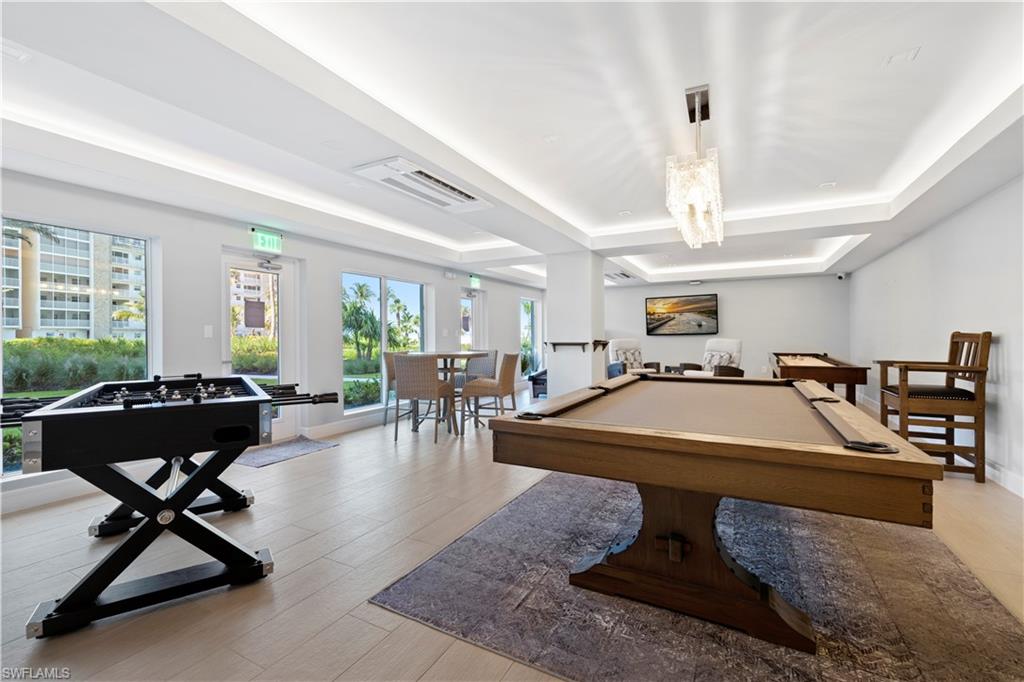 Game room featuring billiards, a raised ceiling, and light wood-style flooring