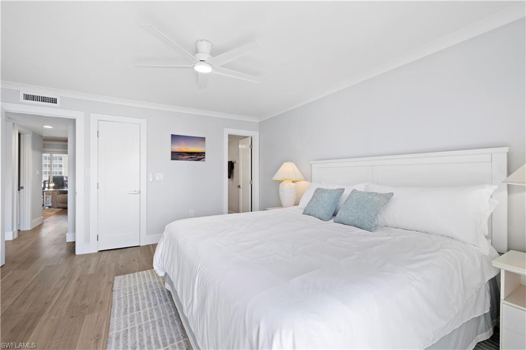 Bedroom featuring light wood-type flooring, ornamental molding, and a ceiling fan
