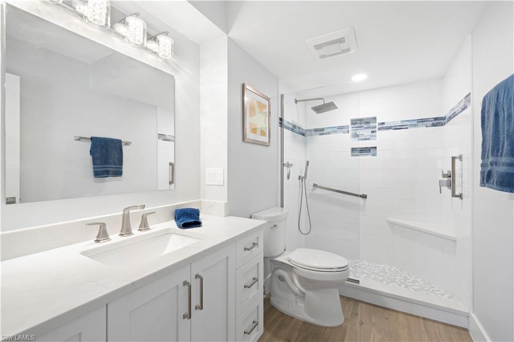 Bathroom with vanity, a tile shower, wood finished floors, and recessed lighting