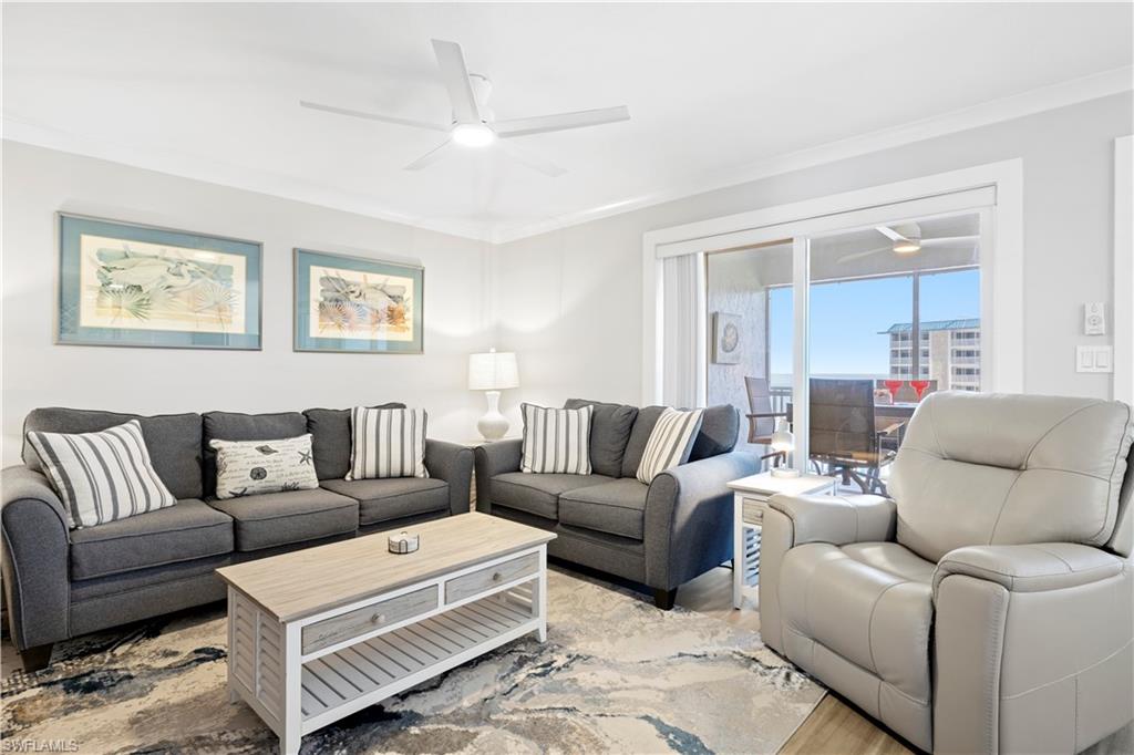 Living area with a ceiling fan, ornamental molding, and light wood-style floors