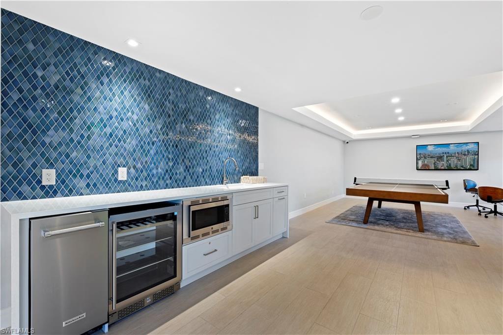 Rec room with beverage cooler, bar with sink, recessed lighting, and a raised ceiling