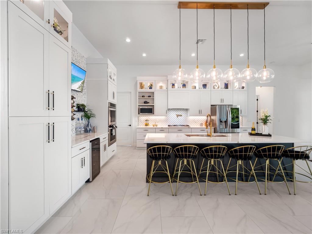 Kitchen featuring glass fronted cabinets, light stone countertops, hanging light fixtures, and a breakfast bar