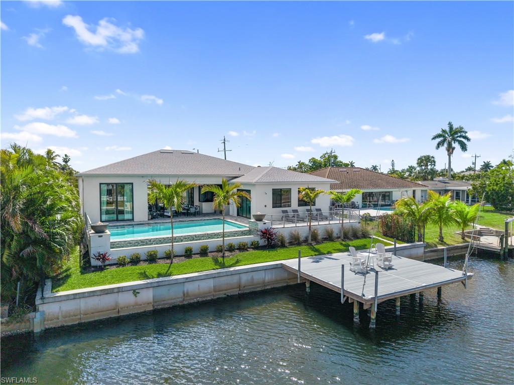 Back of house featuring a patio area, an outdoor pool, and a water view