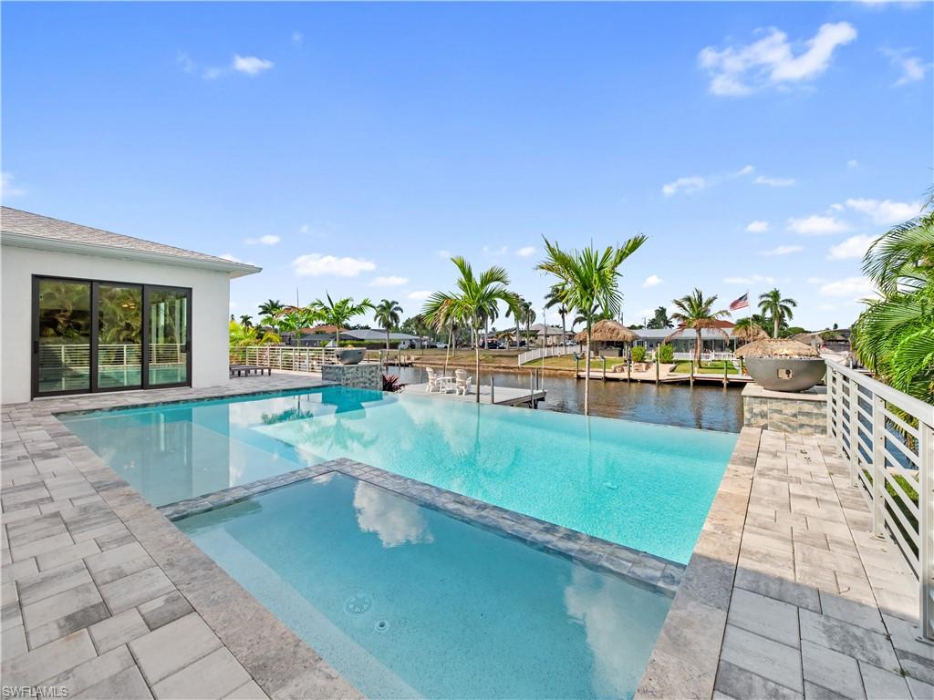 Combined pool / hot tub with a patio area and a water view