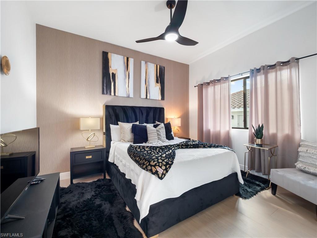 Bedroom featuring ceiling fan, wood finished floors, and an accent wall